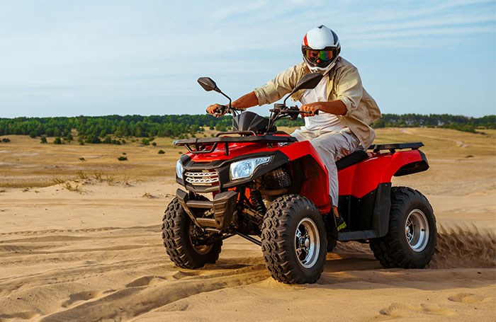man riding an ATV in the dunes